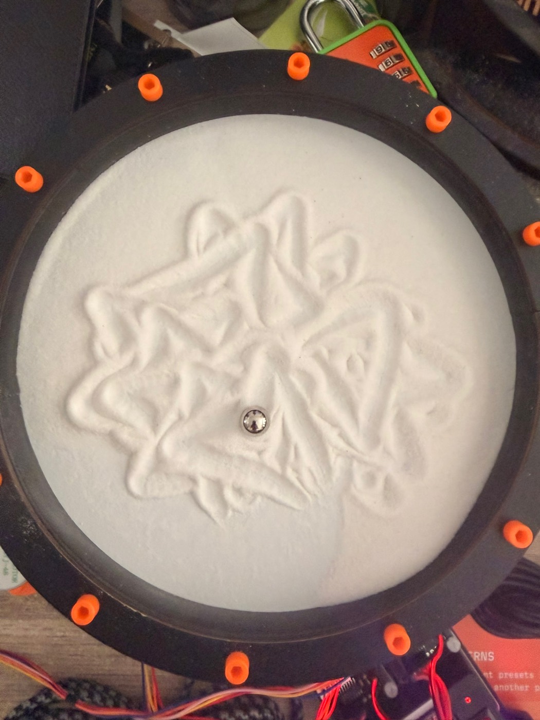 A Maurer rose in white sand: an intricate, roughly six-fold web of straight
chords forming a star of overlapping loops.